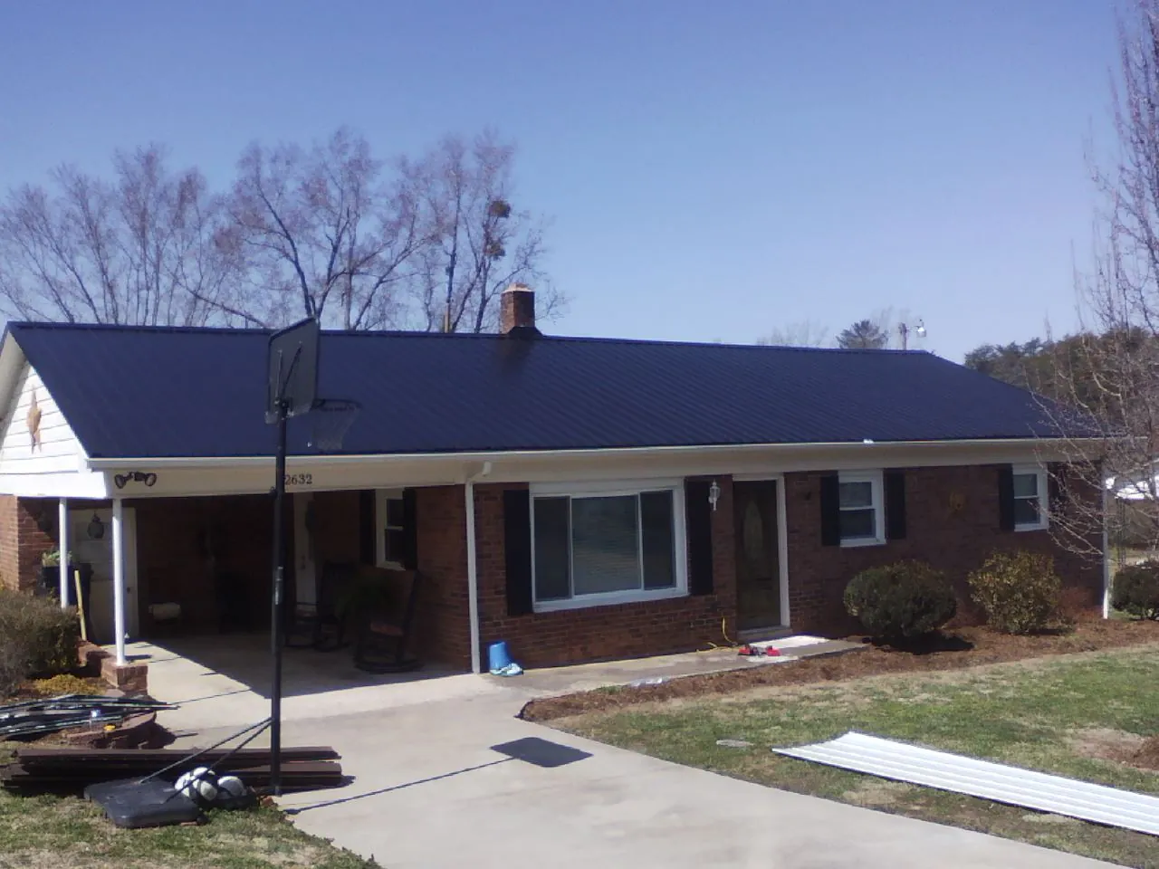 Finished dark blue metal roof on a brick ranch with a carport in Highland Lakes