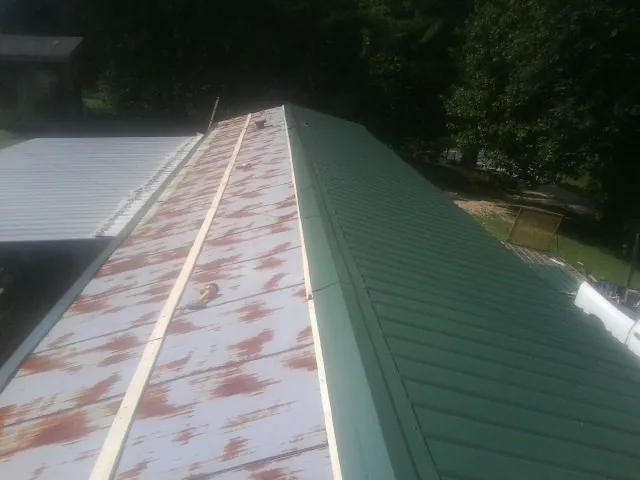 Old rusted panels beside newly installed green metal roofing — Wind Damage Roof Repair by Roofing Brothers in Highland Lakes