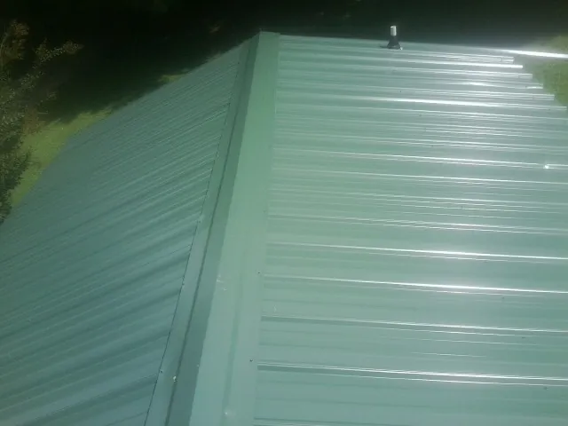 New green metal panels meeting at the ridge of a roof — Flat Roof Repair work by our crew in Highland Lakes
