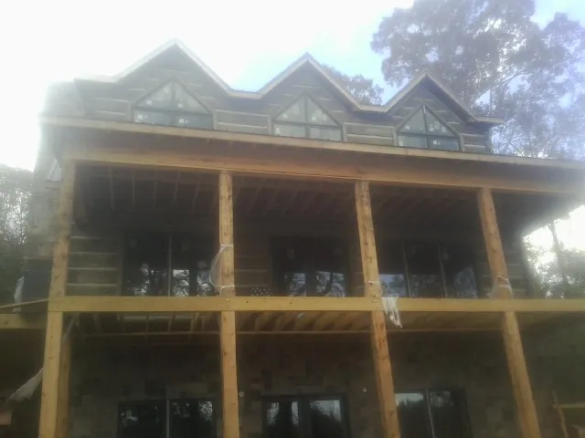 Dormers and porch framing on a large log home under construction — Roof Coating work by our crew in Highland Lakes