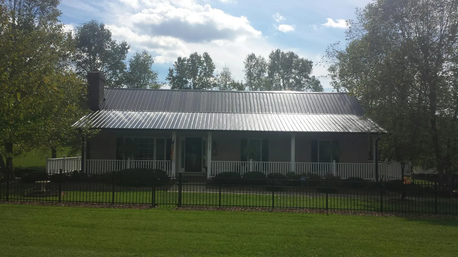 Gray metal roof on a brick ranch with a full width front porch — Gutter Guard Installation work by our crew in Highland Lakes