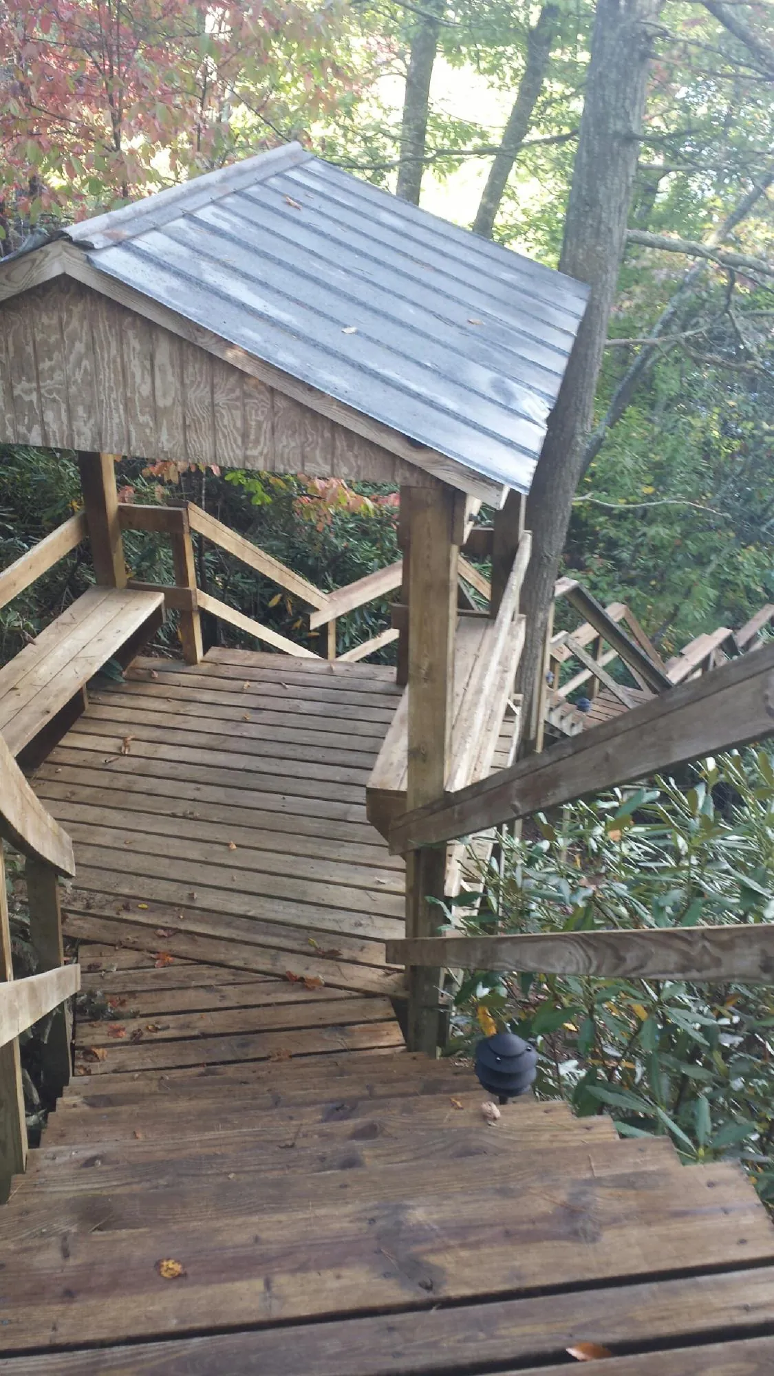 Metal roofed shelter over wooden steps on a wooded walkway — Skylight Repair & Installation work by our crew in Highland Lakes