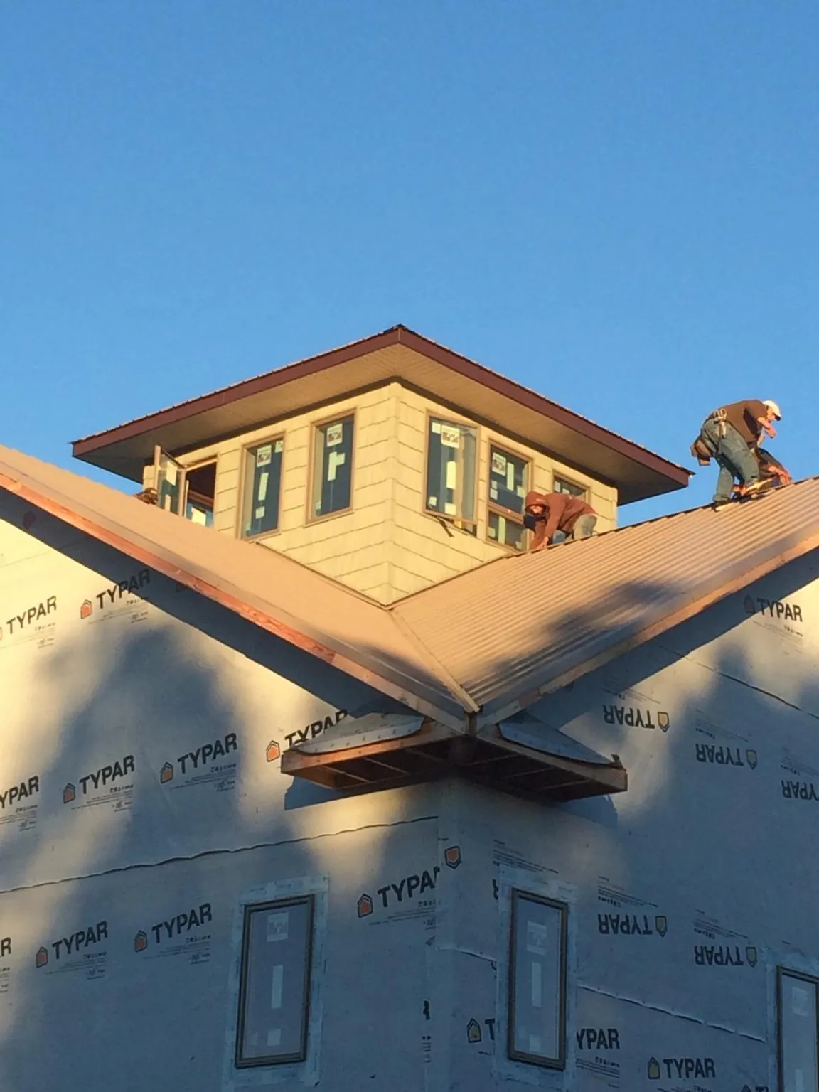Roofers working around a rooftop cupola on a new metal roof at sunset — Roof Waterproofing in Highland Lakes by Roofing Brothers